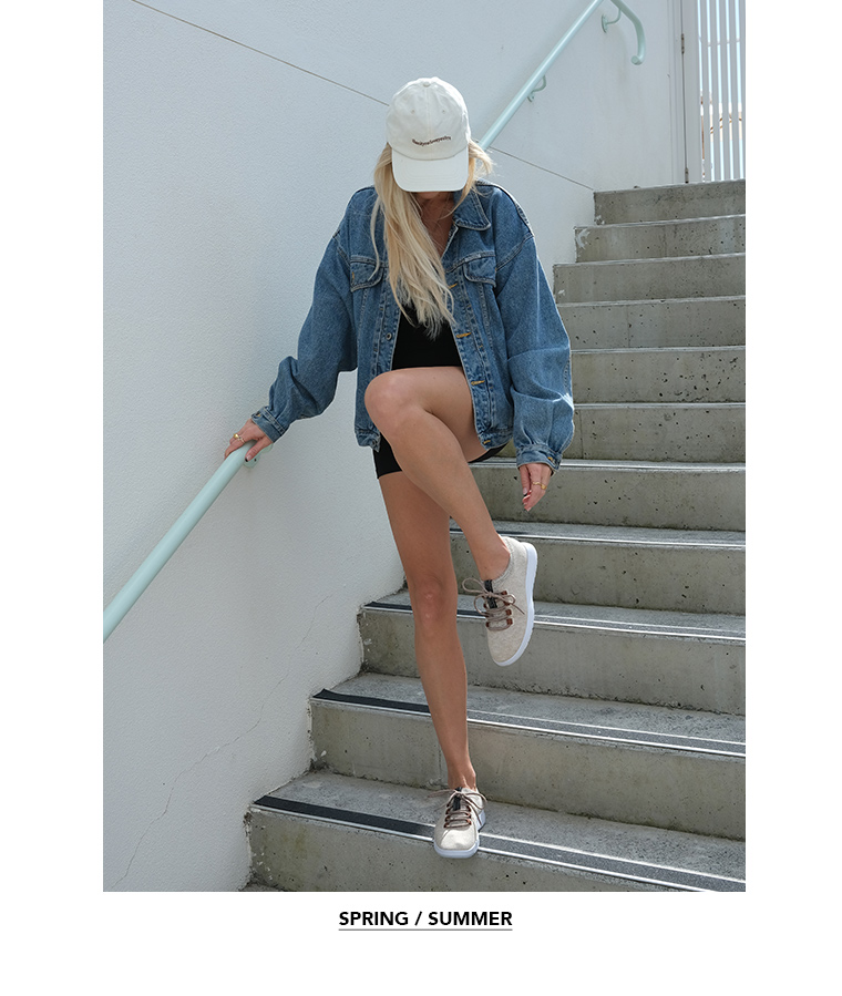 Girl posing in urban setting wearing oversized  demin jacket, shorts, cap and EMU Austraia wool sneakers