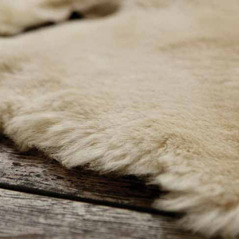 Piece of sheepskin on wood, rolls of merino wool, close-up of leather and lace of boot, close-up of suede, stitching and lace of boot