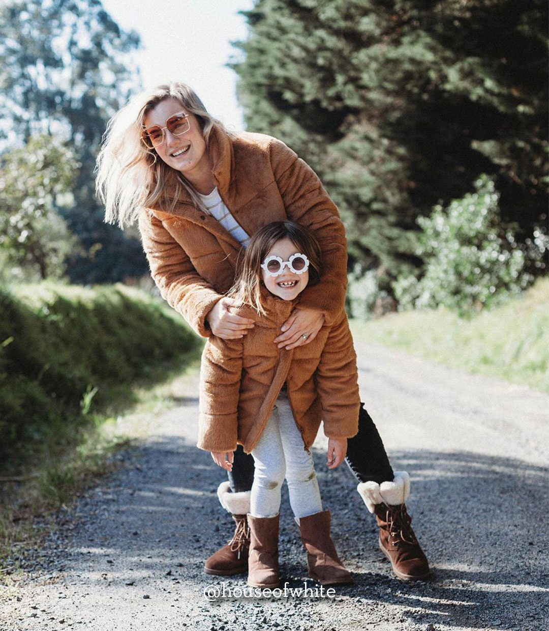 Woman and daughter standing outside and smiling in front of trees wearing EMU boots
