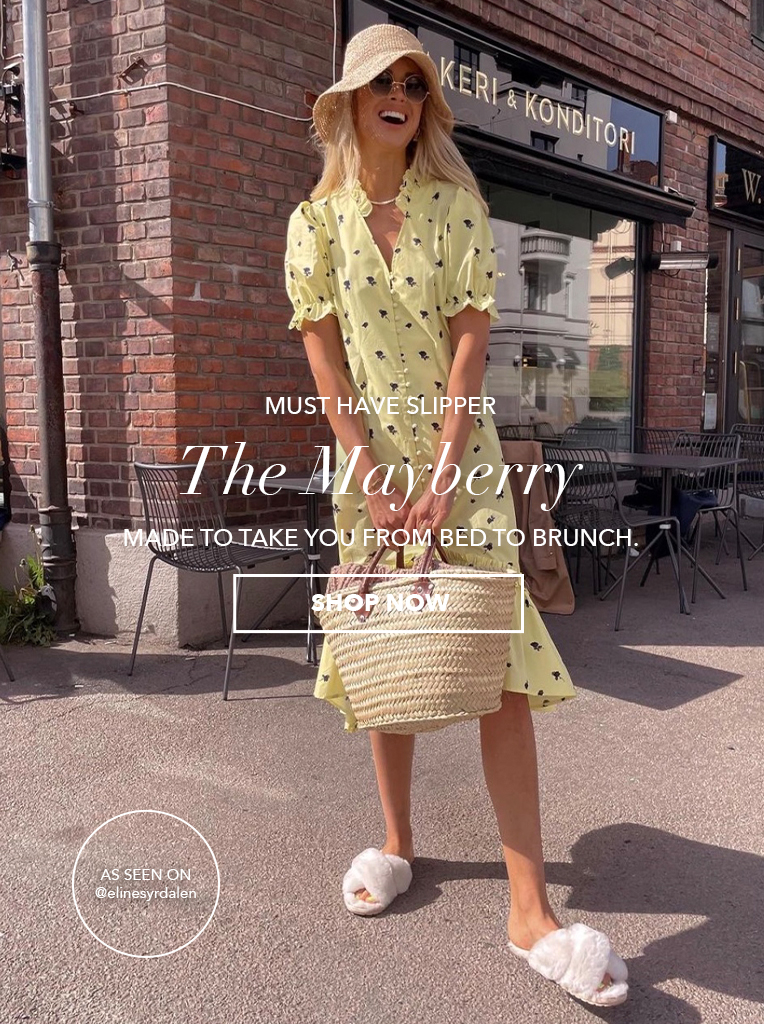 Girl wearing yellow summer dress, floppy hat and Australian sheepskin Mayberry slippers. Must-have Slipper: The Mayberry. Made to take you from bed to brunch. Shop Now.
