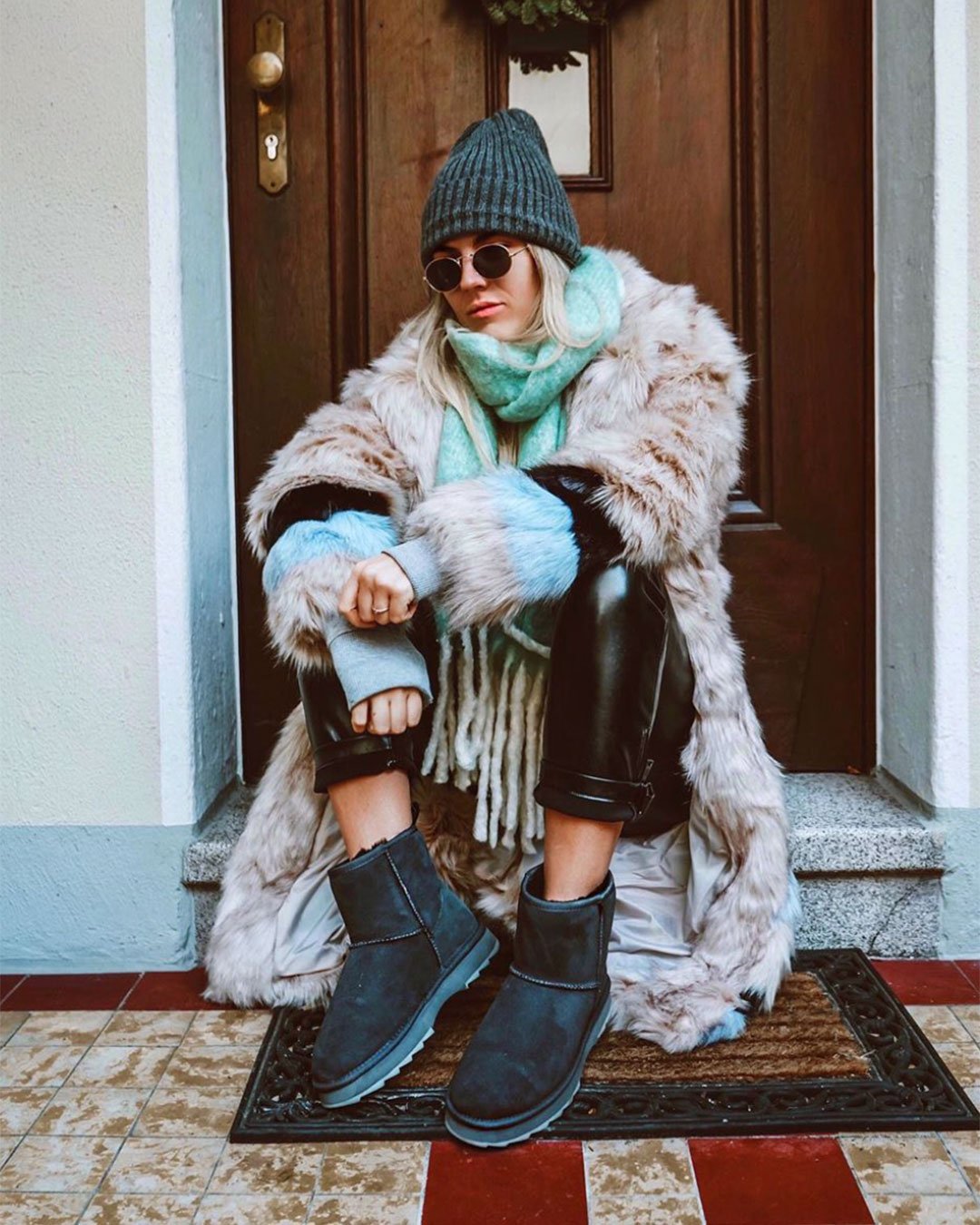 Trendy woman sitting on front doorstep wearing Sharky Mini sheepskin boots