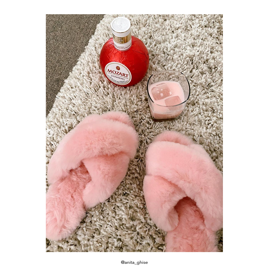 Pink fluffy slippers on shaggy rug next to Mozart strawberry liqueur