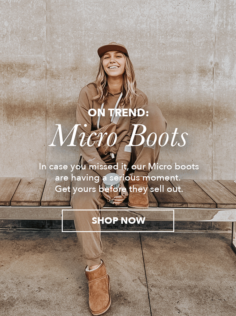 Girl sitting on sidewalk bench wearing matching tracksuit and micro sheepskin boots holding takeaway coffee, text reads, On Trend: Micro Boots. In case you missed it, our Micro boots are having a serious moment. Get yours before they sell out. Shop Now