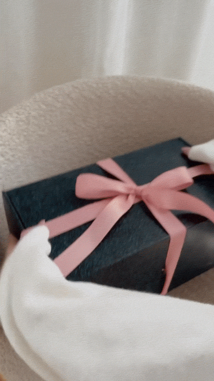 Animated GIF of woman unboxing Platinum Mintaro slippers from luxurious branded EMU Australia packaging