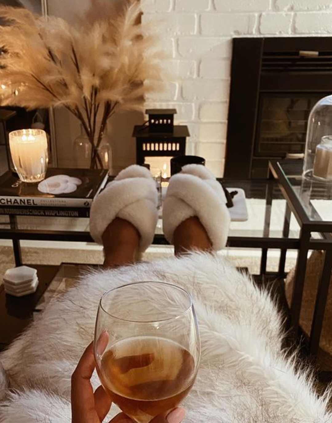 Woman wearing Mayberry sheepskin slippers drinking glass of wine in luxurious and cosy living room