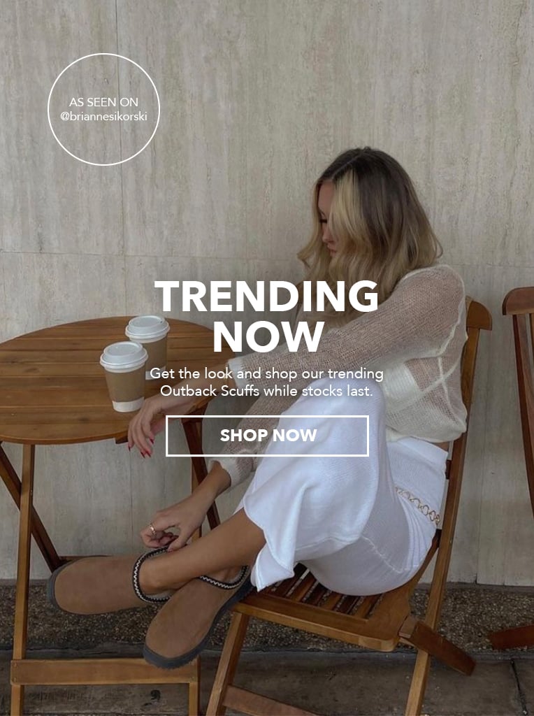 Woman sitting at cafe drinking takeaway coffee wearing Womens Platinum Outback Scuff sheepskin slippers. TRENDING NOW; Get the look and shop out trending Outback Scuffs while stocks last. Shop Now.
