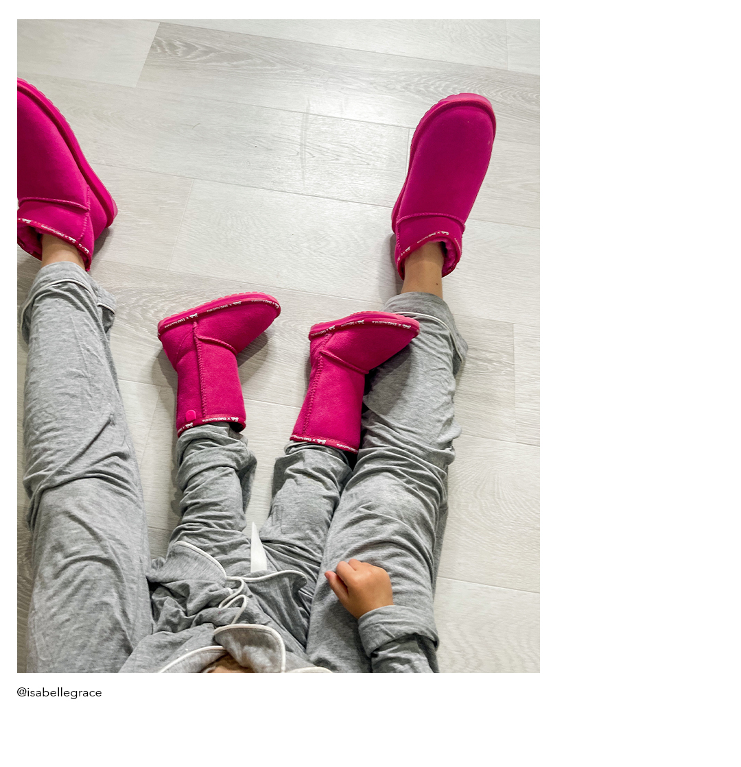 Mum and daughter sitting on floor wearing matching grey pants and pink Barbie sheepskin boots 