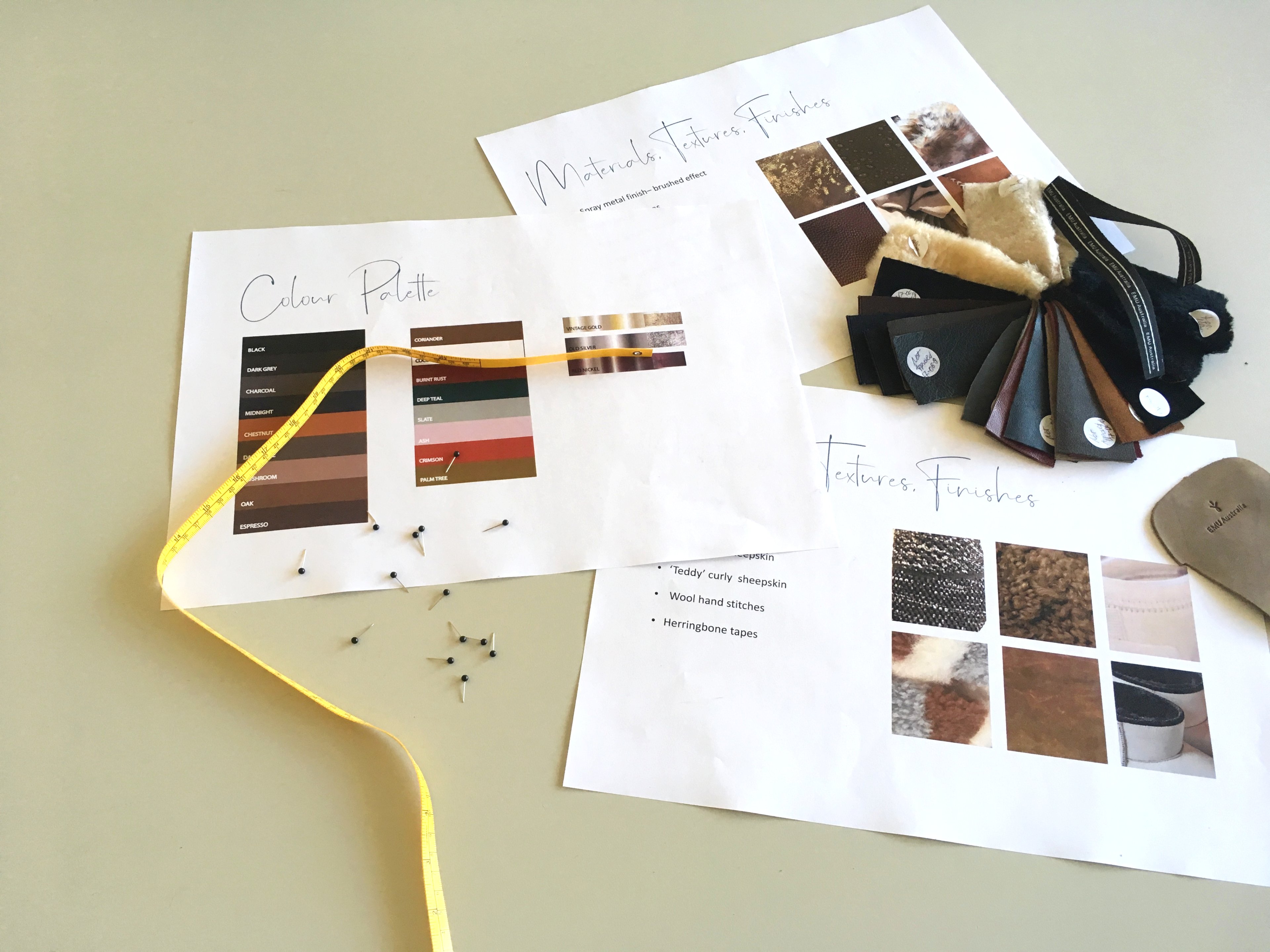 Pieces of paper with design notes, measuring tape, pins, swatches of material sitting on table