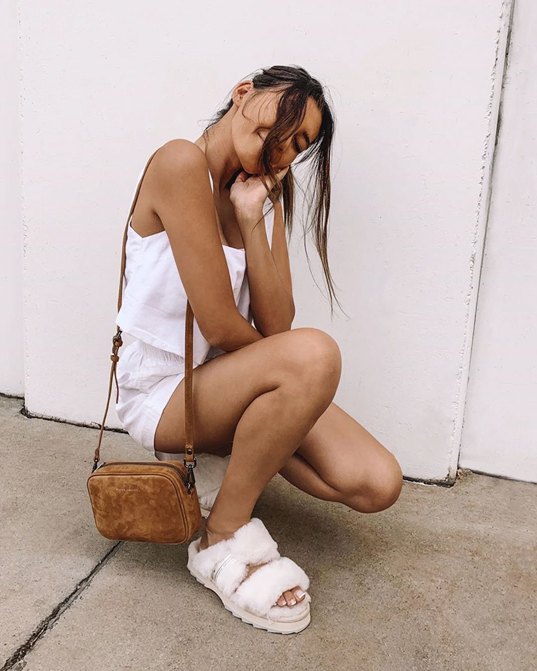 Woman squatting in front of wall wearing Wobbegong sheepskin slippers