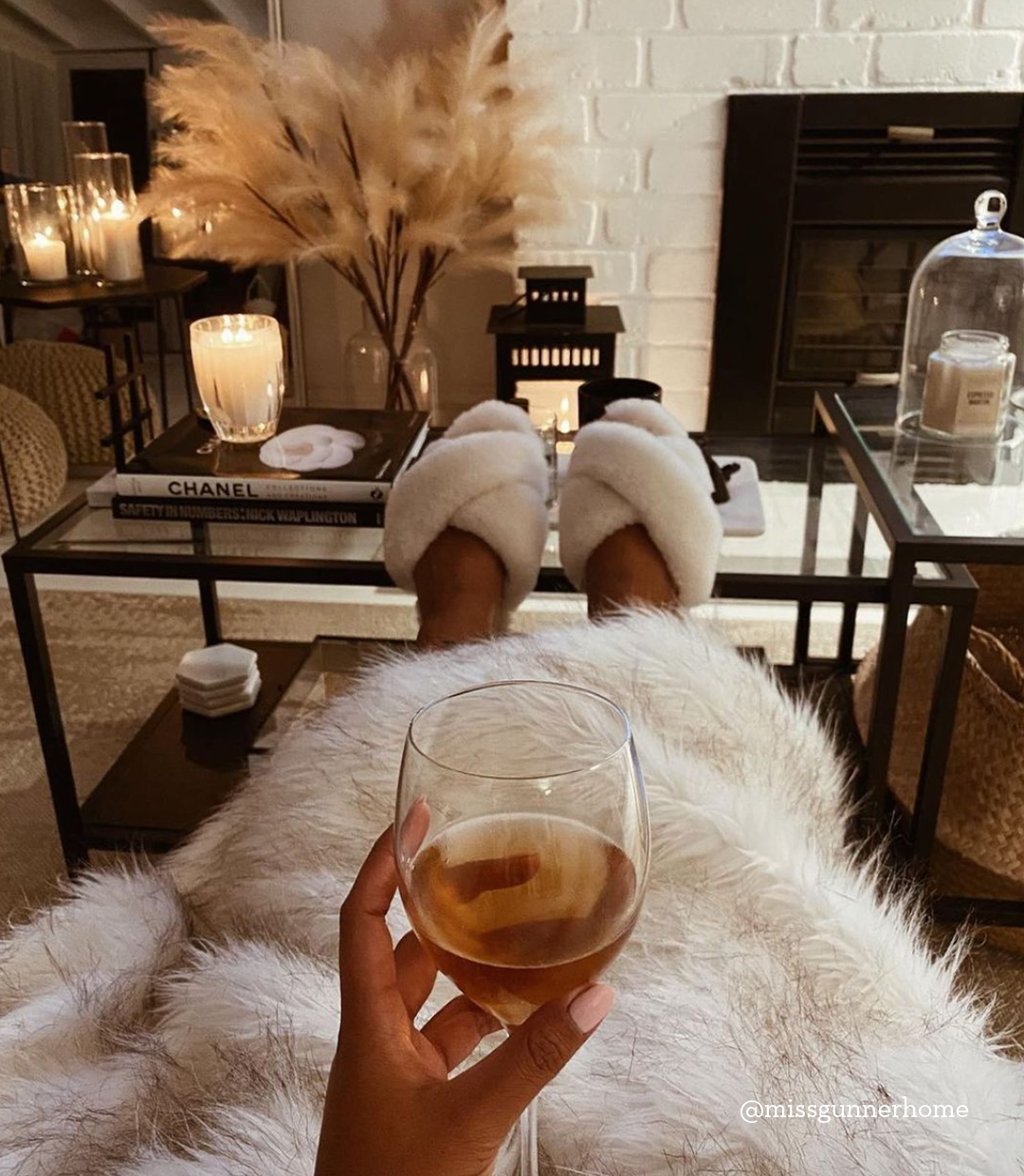 Influencer sitting on couch with glass of wine wearing cosy Mayberry sheepskin slippers