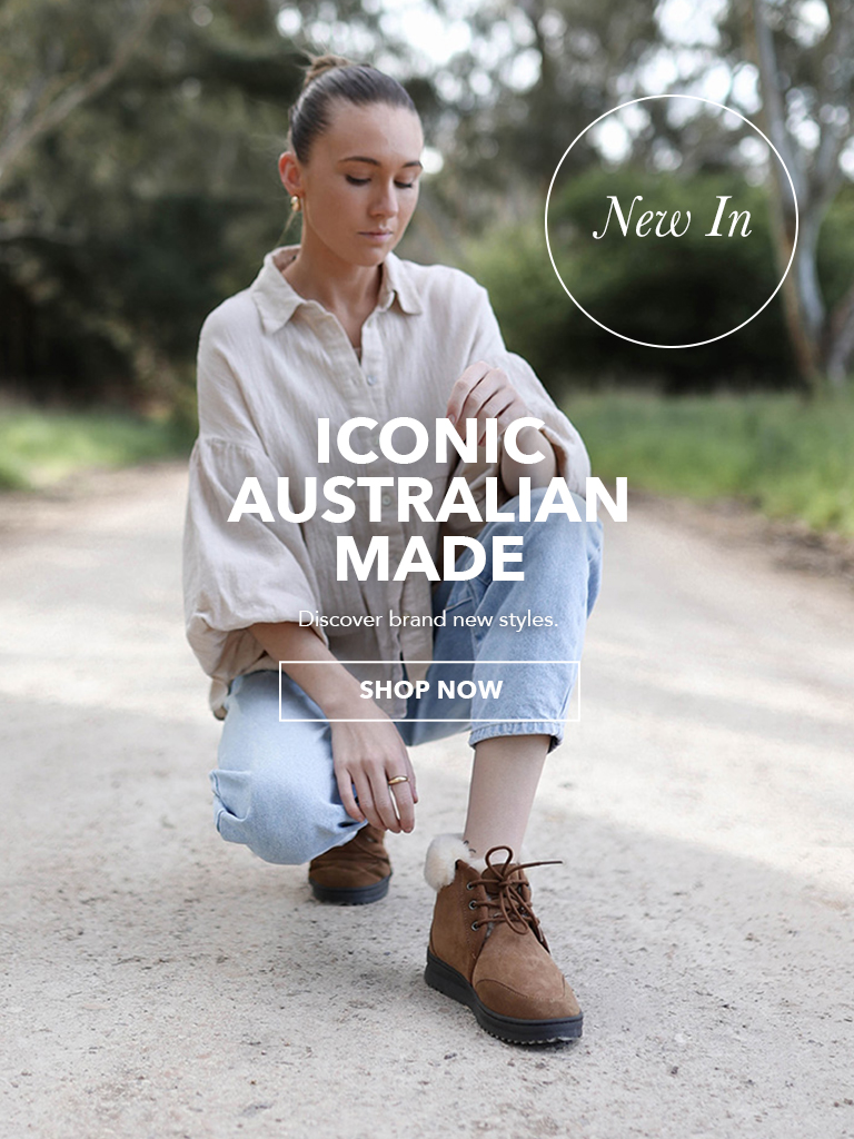 On left: Woman crouching on country dirt road wearing blue jeans, linen top and cuffed sheepskin boots; On left: Man standing on coastal cliff wearing white jeans, knitted grey jumper and brown sheepskin boots. Text reads: New In - Iconic Australian Made. Discover brand new styles. Shop Now