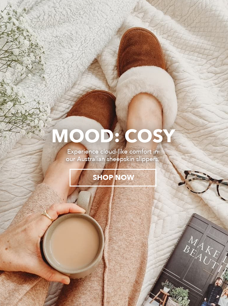 Two women wearing slippers in relaxed setting at home. MOOD: COSY, Experience cloud-like comfort in our Australian sheepskin slippers. Shop Now.